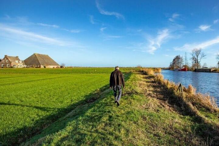 Foto van lopende man in veenweidelandschap